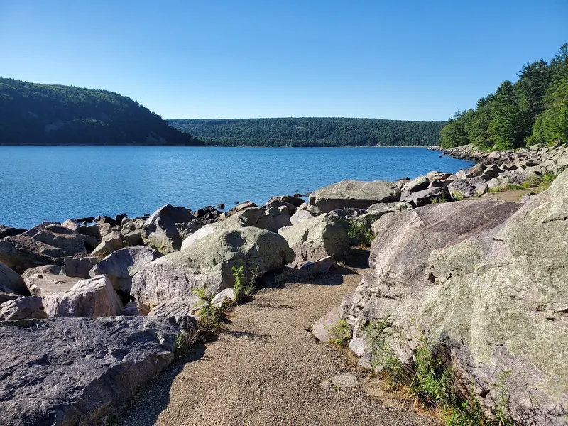 A narrow shoreline path between boulders at Devil's Lake, distinct from the park's sandy swimming beaches